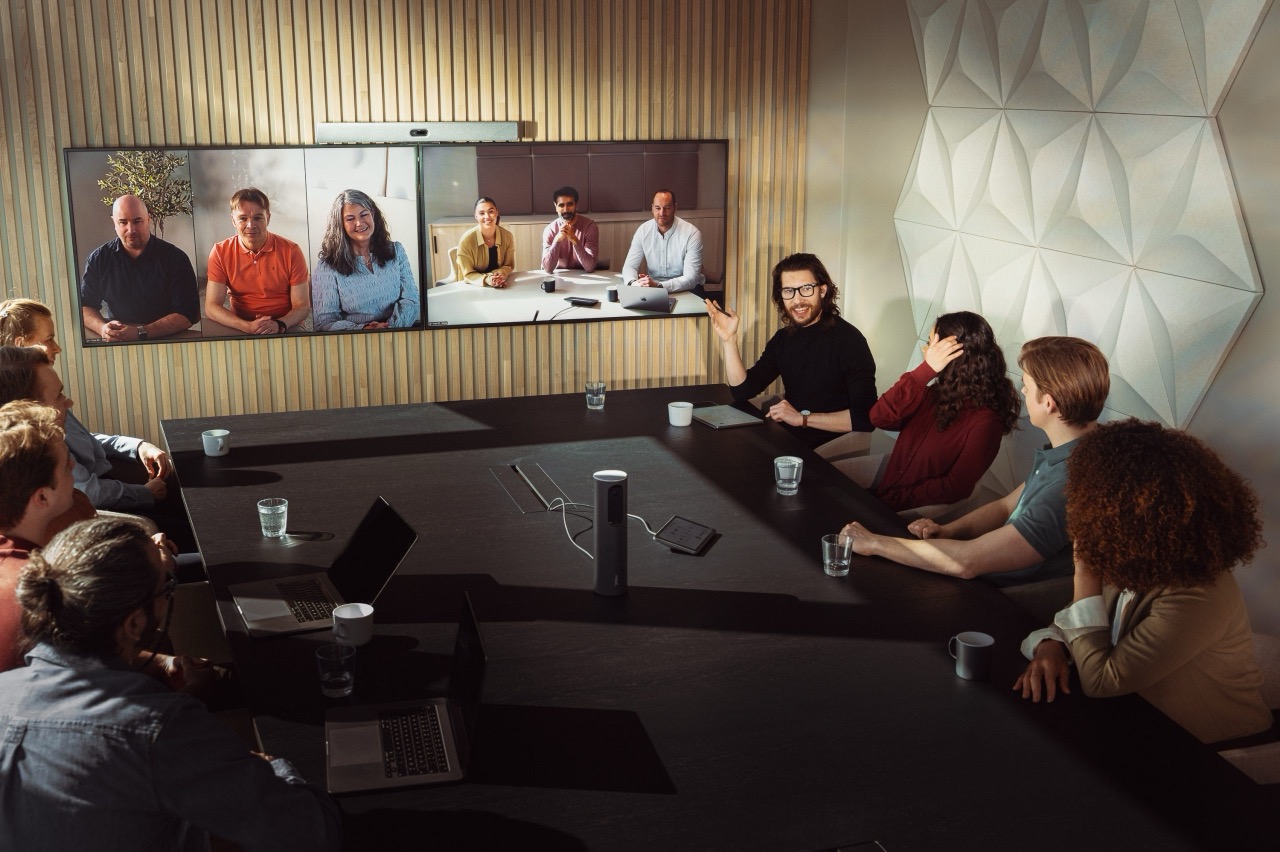 A mid-size meeting room on a video call, with dual displays in front of about ten people.