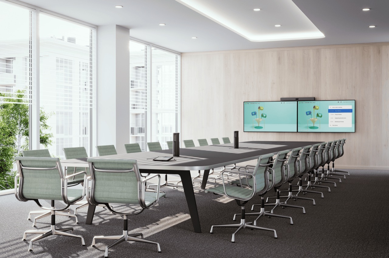 A long boardroom table with executive chairs, facing dual displays on the far wall.