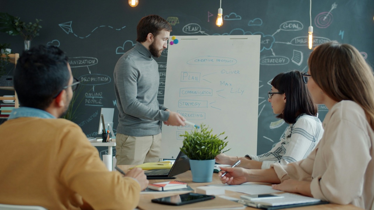 Consultant leading a planning session at a whiteboard with a client team